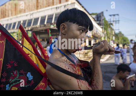 (NOTE AUX ÉDITEURS : l'image contient du contenu graphique.) Les dévotés thaïlandais sont possédés par des esprits et percés avec de longues aiguilles lors d'un rituel végétarien au sanctuaire SAPAM de 19 octobre 2020 à Phuket, en Thaïlande. Le festival végétarien annuel de Phuket, également connu sous le nom de festival des neuf dieux de l'empereur, a commencé sur 17 octobre et se tiendra jusqu'à 25 octobre. Connu pour ses expositions extrêmes de mutilations ritualistes par des médiums d'esprit connu sous le nom de mah chanson le festival est dérivé des croyances taoïstes chinoises. Certains subissent de multiples piercings faciaux avec de grandes aiguilles métalliques et aussi couper leurs langues ouvertes avec des axes, cau Banque D'Images