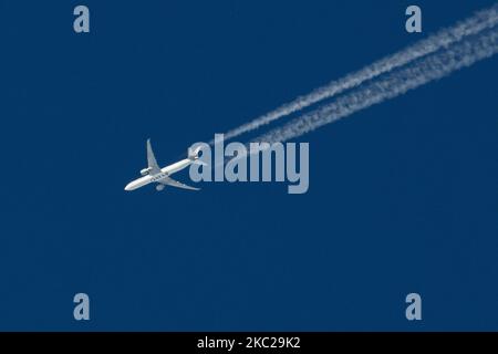 Avion commercial Boeing 777-300ER de Qatar Airways avec le logo d'inscription QATAR visible sur le ventre et le côté de l'avion fuselage, survoler formant des gaz d'échappement moteur contrentre derrière en haute altitude à 38,000 pieds dans le ciel bleu. Le célèbre Boeing triple sept comme vu le 21 octobre 2020 à Eindhoven, pays-Bas dans l'espace aérien de l'Europe au-dessus des pays-Bas, car il vole une route long courrier de l'aéroport de Doha DOH au Qatar à Londres Heathrow LHR au Royaume-Uni, vol QR7 / QTR4LA. L'avion survolant est un Boeing 777 ou B773 avec l'enregistrement A7-BEH et vole avec Banque D'Images