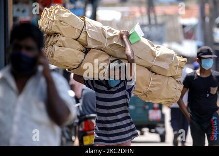 Un portier sri-lankais portant un masque de protection traverse une rue transportant un poids lourd à Colombo, au Sri Lanka. 23 octobre 2020. Le Sri Lanka a enregistré le plus grand nombre de cas confirmés de virus Covid-19 signalés en une journée avec 866 cas, le nombre total de cas confirmés ayant dépassé 7000 alors que le nombre total de patients sous soins médicaux était de 3495 à la fin du vendredi (23) (photo de Thharaka Basnayaka/NurPhoto) Banque D'Images