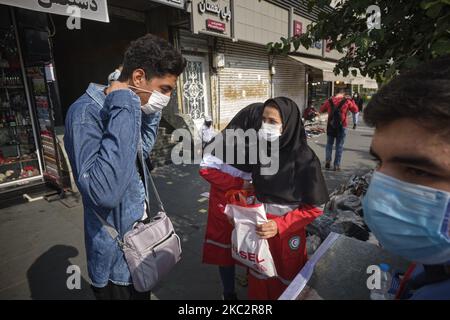 Une femme membre du Croissant-Rouge iranien explique à un homme comment porter un masque facial protecteur pour se prévenir de l’infection par le nouveau coronavirus (COVID-19), dans le quartier des affaires de Téhéran, à 27 octobre 2020. (Photo de Morteza Nikoubazl/NurPhoto) Banque D'Images