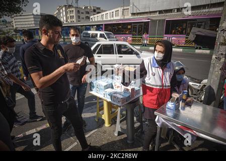 Une femme membre de la Société iranienne du Croissant-Rouge (R) demande à un homme de porter un masque facial protecteur pour se prévenir de l’infection par le nouveau coronavirus (COVID-19), dans le quartier des affaires de Téhéran, à 27 octobre 2020. (Photo de Morteza Nikoubazl/NurPhoto) Banque D'Images