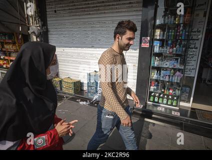 Une femme membre du Croissant-Rouge iranien demande à un homme de porter un masque facial protecteur pour se prévenir de l’infection par le nouveau coronavirus (COVID-19), dans le quartier des affaires de Téhéran, à 27 octobre 2020. (Photo de Morteza Nikoubazl/NurPhoto) Banque D'Images