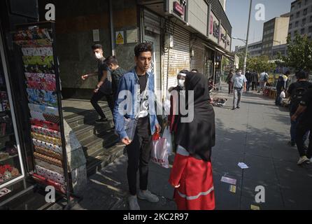 Une femme membre du Croissant-Rouge iranien demande à un homme de porter un masque facial protecteur pour se prévenir de l’infection par le nouveau coronavirus (COVID-19), dans le quartier des affaires de Téhéran, à 27 octobre 2020. (Photo de Morteza Nikoubazl/NurPhoto) Banque D'Images