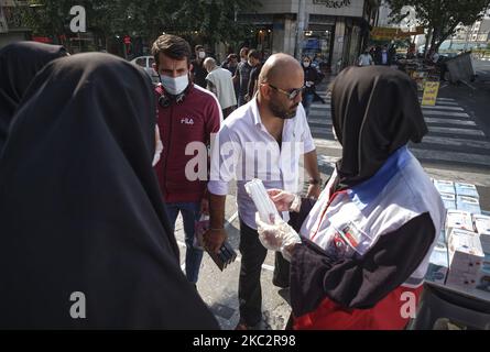 Une femme membre de la Société iranienne du Croissant-Rouge (R) demande à un homme de porter un masque facial protecteur pour se prévenir de l’infection par le nouveau coronavirus (COVID-19), dans le quartier des affaires de Téhéran, à 27 octobre 2020. (Photo de Morteza Nikoubazl/NurPhoto) Banque D'Images