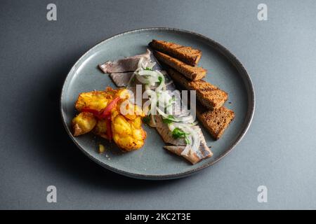 poisson de hareng frais mariné avec pommes de terre et pain brun et oignon isolés Banque D'Images