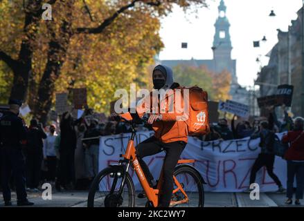 Un service de messagerie de Pyszne.pl à vélo devant les manifestants Pro-Choice dans la vieille ville de Cracovie. Les activistes des droits des femmes et leurs partisans ont organisé leur septième jour de manifestations à Cracovie et dans toute la Pologne, s'opposant à la restriction en cas de pandémie, pour exprimer leur colère contre la décision de la Cour suprême polonaise, qui a resserré les lois déjà strictes sur l'avortement. Sur 28 octobre 2020, à Cracovie, en Pologne. (Photo par Artur Widak/NurPhoto) Banque D'Images