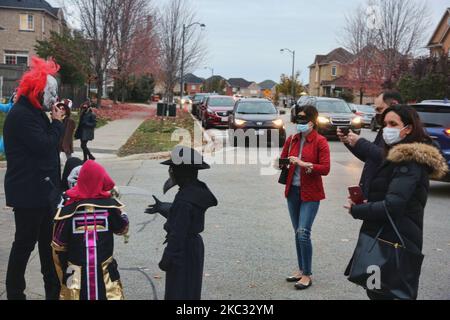 Les enfants et les parents portant un masque facial pour les protéger du nouveau coronavirus (COVID-19) lors de la nuit d'Halloween pendant la pandémie de COVID-19 à Thornhill, Ontario, Canada, on 31 octobre 2020. Il a été conseillé aux résidents de la région de York de célébrer l'Halloween dans leurs foyers et d'éviter les tricks ou les traitements pour aider à ralentir la propagation de la COVID-19) la région de York continue d'être un hotspot pour les infections à la COVID-19 et a récemment été retournée au confinement 2 modifié. (Photo de Creative Touch Imaging Ltd./NurPhoto) Banque D'Images