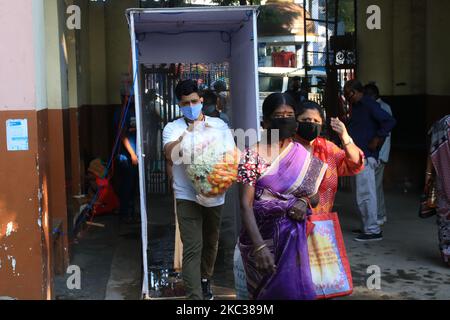 Une famille chrétienne indienne portant un masque facial par mesure de précaution contre le tunnel de désinfection croisée du coronavirus entre dans la tombe alors que les gens visitent un cimetière le jour de tous les souls à Kolkata, Inde, le lundi 2 novembre 2020. La journée honore les morts tandis que les amis et les familles se réunissent dans des cimetières pour décorer les tombes de leurs proches avec des bougies et des fleurs et offrir des prières. (Photo de Debajyoti Chakraborty/NurPhoto) Banque D'Images