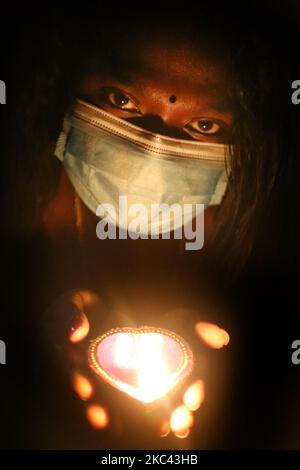 Femme hindoue portant un masque facial pour la protéger du nouveau coronavirus (COVID-19), alors qu'elle détient une diya (petite lampe en argile) pendant le festival de Diwali à un temple hindou à Toronto, Ontario, Canada, on 14 novembre 2020. (Photo de Creative Touch Imaging Ltd./NurPhoto) Banque D'Images