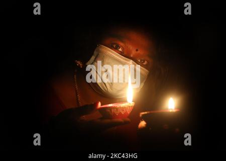 Femme hindoue portant un masque facial pour la protéger du nouveau coronavirus (COVID-19) comme elle détient des diyas (petites lampes en argile) pendant le festival de Diwali à un temple hindou à Toronto, Ontario, Canada, on 14 novembre 2020. (Photo de Creative Touch Imaging Ltd./NurPhoto) Banque D'Images