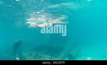 Une femme vue nager au-dessus de l'épave. Images sous-marines dans la mer Egée de l'ancien naufrage rouillé en eau peu profonde avec la faune des poissons à la plage de Potamos Epanomi près de Thessalonique en Grèce. L'épave est proche de la plage de sable et est un monument pour la région, un point de repère pour les habitants et les touristes attirant les gens pour nager au-dessus de lui, plongée avec tuba, plongée sous-marine ou de s'amuser à la plage avec l'eau cristalline de la mer. 10 octobre 2020 (photo de Nicolas Economou/NurPhoto) Banque D'Images