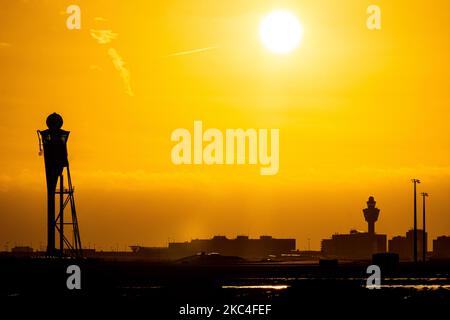 Heure d'or de l'aube et du lever du soleil avec couleurs chaudes du ciel de l'heure magique à l'aéroport international ECAM d'Amsterdam Schiphol AMS aux pays-Bas. Images tôt le matin de l'industrie de l'aviation avec la silhouette de la tour de contrôle et de l'avion d'atterrissage dans le paysage de SkyScape européen coloré. 22 novembre 2020 (photo de Nicolas Economou/NurPhoto) Banque D'Images