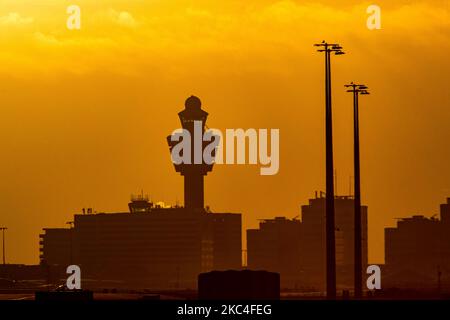 Heure d'or de l'aube et du lever du soleil avec couleurs chaudes du ciel de l'heure magique à l'aéroport international ECAM d'Amsterdam Schiphol AMS aux pays-Bas. Images tôt le matin de l'industrie de l'aviation avec la silhouette de la tour de contrôle et de l'avion d'atterrissage dans le paysage de SkyScape européen coloré. 22 novembre 2020 (photo de Nicolas Economou/NurPhoto) Banque D'Images