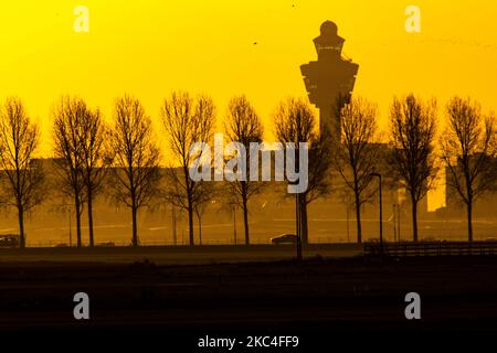 Heure d'or de l'aube et du lever du soleil avec couleurs chaudes du ciel de l'heure magique à l'aéroport international ECAM d'Amsterdam Schiphol AMS aux pays-Bas. Images tôt le matin de l'industrie de l'aviation avec la silhouette de la tour de contrôle et de l'avion d'atterrissage dans le paysage de SkyScape européen coloré. 22 novembre 2020 (photo de Nicolas Economou/NurPhoto) Banque D'Images