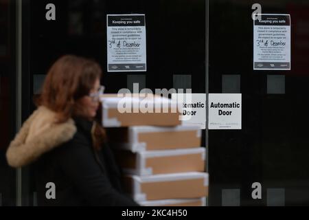 Une femme transportant des boîtes se promène près d'une fenêtre de magasin avec un avis informant d'une fermeture temporaire de magasin, vue dans le centre-ville de Dublin. Lundi, 23 novembre 2020, à Dublin, Irlande. (Photo par Artur Widak/NurPhoto) Banque D'Images