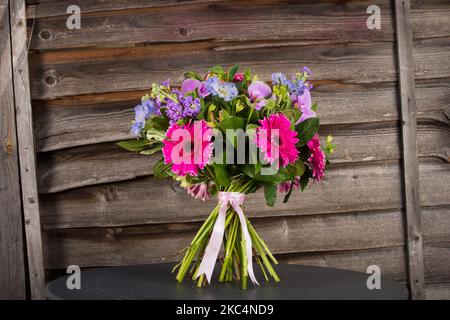 Un bouquet de fleurs gerbera coloré sur une table grise avec fond en bois Banque D'Images