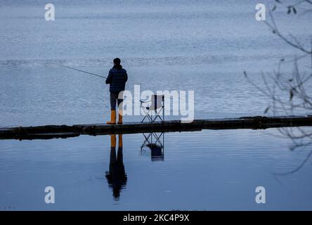 South Lake, Craigavon, comté d'Armagh, Irlande du Nord, Royaume-Uni. 4 novembre 2022. Temps au Royaume-Uni - un calme principalement couvert jour après une nuit froide que la haute pression domine pendant quelques heures. Un pêcheur à la ligne dans des puits de lumière jaune pêche grossière pour le brochet en fin d'après-midi. Crédit : CAZIMB/Alamy Live News. Banque D'Images