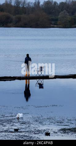 South Lake, Craigavon, comté d'Armagh, Irlande du Nord, Royaume-Uni. 4 novembre 2022. Temps au Royaume-Uni - un calme principalement couvert jour après une nuit froide que la haute pression domine pendant quelques heures. Un pêcheur à la ligne dans des puits de lumière jaune pêche grossière pour le brochet en fin d'après-midi. Crédit : CAZIMB/Alamy Live News. Banque D'Images