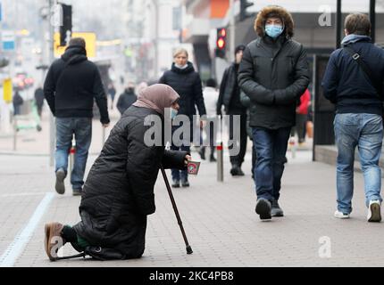 Le 27 novembre 2020, une femme âgée portant un masque facial protecteur dans le cadre de l'épidémie du coronavirus COVID-19 demande des almes à genoux dans le centre de Kiev, en Ukraine. (Photo par STR/NurPhoto) Banque D'Images