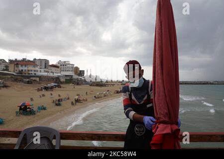 Un travailleur palestinien portant un masque facial de protection dans un café près d'une plage dans la ville de Gaza lors d'une forte pluie dans la ville de Gaza, sur 5 décembre 2020. (Photo de Majdi Fathi/NurPhoto) Banque D'Images
