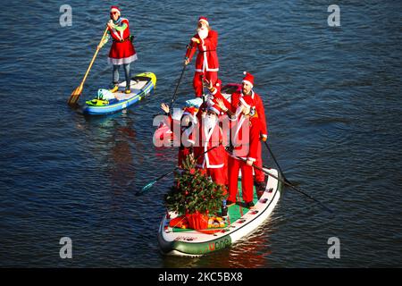 Les surfeurs en paddleboard vêtus des costumes du Père Noël flottent sur la Vistule lors d'un événement caritatif le jour de Saint Nicolas à Cracovie, en Pologne. 6 décembre 2020. (Photo de Beata Zawrzel/NurPhoto) Banque D'Images