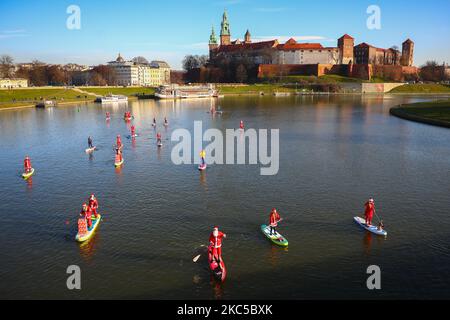 Les surfeurs en paddleboard vêtus des costumes du Père Noël flottent sur la Vistule lors d'un événement caritatif le jour de Saint Nicolas à Cracovie, en Pologne. 6 décembre 2020. (Photo de Beata Zawrzel/NurPhoto) Banque D'Images