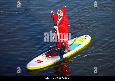 Les surfeurs en paddleboard vêtus des costumes du Père Noël flottent sur la Vistule lors d'un événement caritatif le jour de Saint Nicolas à Cracovie, en Pologne. 6 décembre 2020. (Photo de Beata Zawrzel/NurPhoto) Banque D'Images