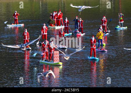 Les surfeurs en paddleboard vêtus des costumes du Père Noël flottent sur la Vistule lors d'un événement caritatif le jour de Saint Nicolas à Cracovie, en Pologne. 6 décembre 2020. (Photo de Beata Zawrzel/NurPhoto) Banque D'Images