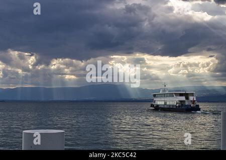 Un navire isolé dans le lac de Genève entre la France et la Suisse sous la lumière du soleil venant à travers les nuages Banque D'Images