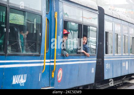 Enfants vus des fenêtres ouvertes du train. Le Darjeeling Himalayan Railway ou DHR ou connu comme Toy train en raison de la voie étroite 2ft sur les pentes de l'Himalaya en Inde. Le train relie New Jalpaiguri et Darjeeling au Bengale-Occidental, construit en 1881 et atteint une altitude de 2200m. Au-dessus du niveau de la mer. La locomotive utilise du diesel, mais des locomotives à vapeur de classe B sont également utilisées et font le trajet entre les habitants et les touristes de Ghum et Darjeeling, avec une vue panoramique sur les montagnes, les pentes, la plantation de thé et passent des villes à côté des maisons et des marchés. Depuis 1999 Banque D'Images