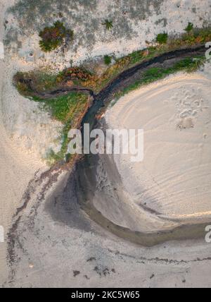 Petit ruisseau de rivière qui coule à l'océan à travers une plage de sable Banque D'Images