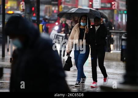 Les femmes se réfugient sous un parapluie lors d'une descente au cirque d'Oxford à Londres, en Angleterre, sur 19 décembre 2020. Londres et de grandes parties du sud-est de l'Angleterre seront placées sous une nouvelle 'Tier 4' de restrictions de coronavirus à partir de minuit ce soir, a annoncé le Premier ministre britannique Boris Johnson cet après-midi, répondre aux préoccupations des autorités au sujet de la propagation d'une souche plus infectieuse du coronavirus qui, semble-t-il, entraîne des hospitalisations dans ces régions du pays. Selon les règles du niveau 4, les magasins non essentiels doivent fermer, tout comme les coiffeurs, les bars à ongles, les salles de gym et les loisirs Banque D'Images