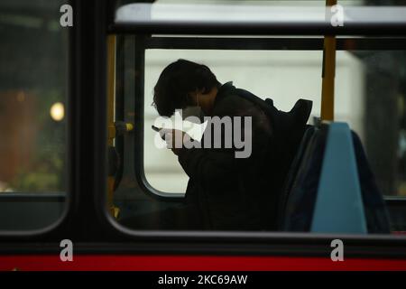 Un passager portant un masque utilise son téléphone dans un bus sur Regent Street à Londres, en Angleterre, sur 21 décembre 2020. Londres a passé sa deuxième journée de ce qui pourrait être des mois sous les nouvelles restrictions de 'Tier 4' du coronavirus aujourd'hui. En vertu des règles de niveau 4, les magasins non essentiels et de nombreuses autres entreprises, y compris les salles de sport et les coiffeurs, doivent fermer, les personnes ayant reçu l'instruction de rester à la maison autre que pour des circonstances exemptées, y compris les voyages au travail ou à l'éducation. Le mélange à l'intérieur entre ceux des différents ménages est également interdit sous le nouveau niveau, ce qui a bouleverser les plans de Noël pour une immense partie de la population Banque D'Images