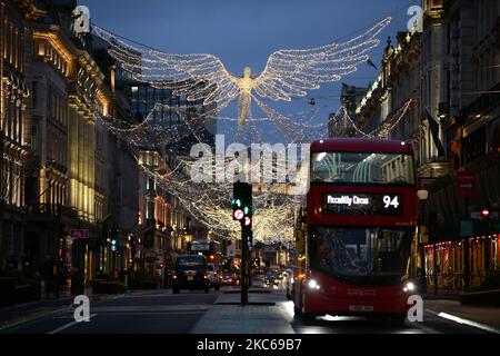 Un bus passe sous les feux de Noël sur Regent Street à Londres, en Angleterre, sur 21 décembre 2020. Londres a passé sa deuxième journée de ce qui pourrait être des mois sous les nouvelles restrictions de 'Tier 4' du coronavirus aujourd'hui. En vertu des règles de niveau 4, les magasins non essentiels et de nombreuses autres entreprises, y compris les salles de sport et les coiffeurs, doivent fermer, les personnes ayant reçu l'instruction de rester à la maison autre que pour des circonstances exemptées, y compris les voyages au travail ou à l'éducation. Le mélange à l'intérieur entre les ménages est également interdit sous le nouveau niveau, ce qui a bouleverser les plans de Noël pour une immense partie de la population. Problème Banque D'Images