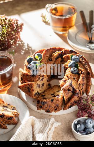 Gâteau aux myrtilles en tranches décoré de baies et de thé, concept de petit déjeuner festif ensoleillé le matin, temps de thé Banque D'Images