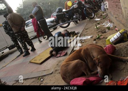 Un homme sans abri avec un chien dort sur un trottoir à l'extérieur d'une église pendant une soirée hivernale froide à New Delhi, Inde sur 25 décembre 2020. (Photo de Mayank Makhija/NurPhoto) Banque D'Images