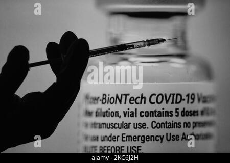 Une image d'illustration d'une seringue médicale devant une image d'un flacon contenant le vaccin Pfizer-BionTech affichée sur les écrans. Lundi, 28 décembre 2020, à Dublin, Irlande. (Photo par Artur Widak/NurPhoto) Banque D'Images