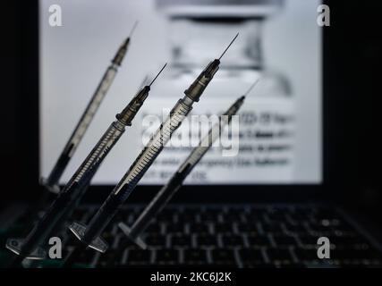 Une image d'illustration de seringues médicales vue devant une image d'un flacon contenant le vaccin Pfizer-BionTech affichée à l'écran. Lundi, 28 décembre 2020, à Dublin, Irlande. (Photo par Artur Widak/NurPhoto) Banque D'Images