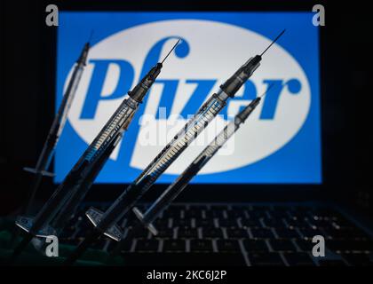 Une image d'illustration des seringues médicales vues devant le logo de Pfizer affichée à l'écran. Lundi, 28 décembre 2020, à Dublin, Irlande. (Photo par Artur Widak/NurPhoto) Banque D'Images