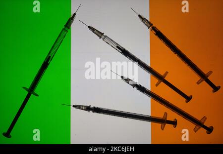 Une illustration des seringues médicales vues devant le drapeau de la République d'Irlande. La vaccination contre la COVID en Irlande commence aujourd'hui, un jour plus tôt que prévu, après avoir augmenté la pression sur les services de santé. Un petit nombre de personnes dans quatre hôpitaux de Dublin recevront leur première vaccination. L'Allemagne, la Hongrie et la Slovaquie ont lancé la campagne de vaccination COVID-19 le samedi 26 décembre, une journée plus tôt que le déploiement coordonné prévu par la Commission européenne dans tous les États membres. Mardi, 29 décembre 2020, à Dublin, Irlande. (Illustration photo par Artur Widak/NurPhoto) Banque D'Images