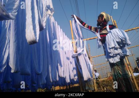 Un ouvrier bangladais répand du tissu sur un porte-bambou après les avoir teints dans une usine de Narayanganj, à environ 20 kilomètres de Dhaka vendredi, 01 janvier 2021. (Photo de Syed Mahamudur Rahman/NurPhoto) Banque D'Images