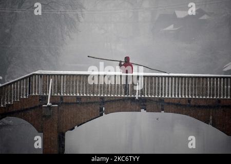 Un homme traversant un pont de pied pendant qu'il neige à Srinagar sur 03 janvier 2021. Le département météorologique indien a prédit une chute de neige modérée à travers le Cachemire et une forte chute de neige dans des régions plus hautes. La route de 270 kilomètres Srinagar-Jammu la seule route reliant le Cachemire à d'autres parties du pays a été fermée après une chute de neige fraîche. Au moins quinze personnes ont été blessées dans différents accidents de la route à travers Jammu-et-Cachemire en raison de routes glissantes, a rapporté une agence de presse locale. (Photo par Faisal Khan/NurPhoto) Banque D'Images