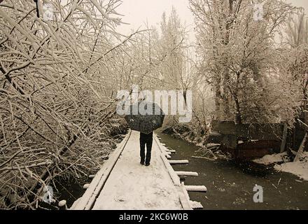 Un homme marche sur un pont couvert de neige alors qu'il neige à Srinagar sur 03 janvier 2021. Le département météorologique indien a prédit une chute de neige modérée à travers le Cachemire et une forte chute de neige dans des régions plus hautes. La route de 270 kilomètres Srinagar-Jammu la seule route reliant le Cachemire à d'autres parties du pays a été fermée après une chute de neige fraîche. Au moins quinze personnes ont été blessées dans différents accidents de la route à travers Jammu-et-Cachemire en raison de routes glissantes, a rapporté une agence de presse locale. (Photo par Faisal Khan/NurPhoto) Banque D'Images