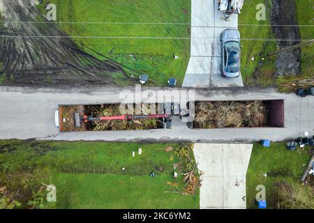 Vue aérienne de l'ouragan Ian après les secours camion-benne ramassant les débris de végétation des rues suburbaines de Floride. Traiter avec Banque D'Images