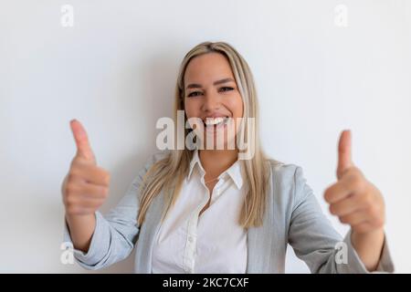 Un médecin professionnel souriant en uniforme médical vous montre les pouces. Une femme médecin souriante et satisfaite, recommandant un produit, fond blanc Banque D'Images