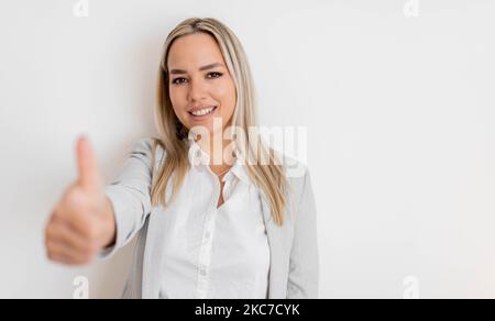 Un médecin professionnel souriant en uniforme médical vous montre les pouces. Une femme médecin souriante et satisfaite, recommandant un produit, fond blanc Banque D'Images