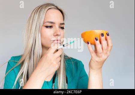 Scientifique mettant un nouvel échantillon dans les fruits. La scientifique femelle injecte la substance dans le fruit. Les pesticides et les nitrates sont injectés par un scientifique dans Banque D'Images