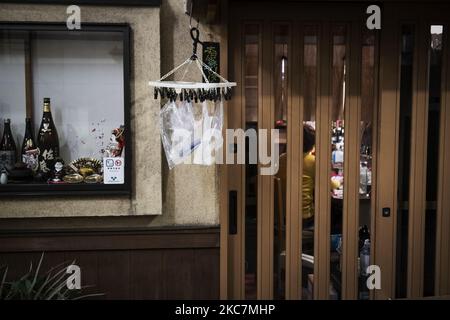 Le 11 janvier 2021, des gants jetables et des sacs en plastique sont suspendus sur un cintre devant un bar japonais fermé dans le quartier de la vie nocturne de Tokyo, au Japon. (Photo par Yusuke Harada/NurPhoto) Banque D'Images