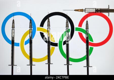 Une photo d'illustration montrant des seringues médicales vues devant le drapeau olympique affiché à l'écran. Lundi, 18 janvier 2021, à Dublin, Irlande. (Photo par Artur Widak/NurPhoto) Banque D'Images