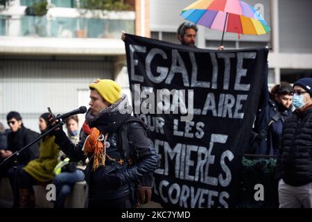 Une jeune femme parle alors que des activistes mettent derrière une bannière "des salaires égaux pour les premières femmes de la partie rodée". Des travailleurs de la culture (acteurs, artistes en direct, musiciens, techniciens, etc.) et des activistes ont organisé une représentation dans les rues de Toulouse pour protester contre la fermeture de tous les théâtres, cinémas, salles de concert, etc. Par le gouvernement français en raison de la pandémie de Covid-19. Ils ont également fait cela dans la défense des services publics tels que Pole emploi (agence pour les chômeurs), CAF (organisme qui paie des allocations familiales) ou la sécurité sociale. Toulouse. France. 21 janvier 2021. (Photo b Banque D'Images